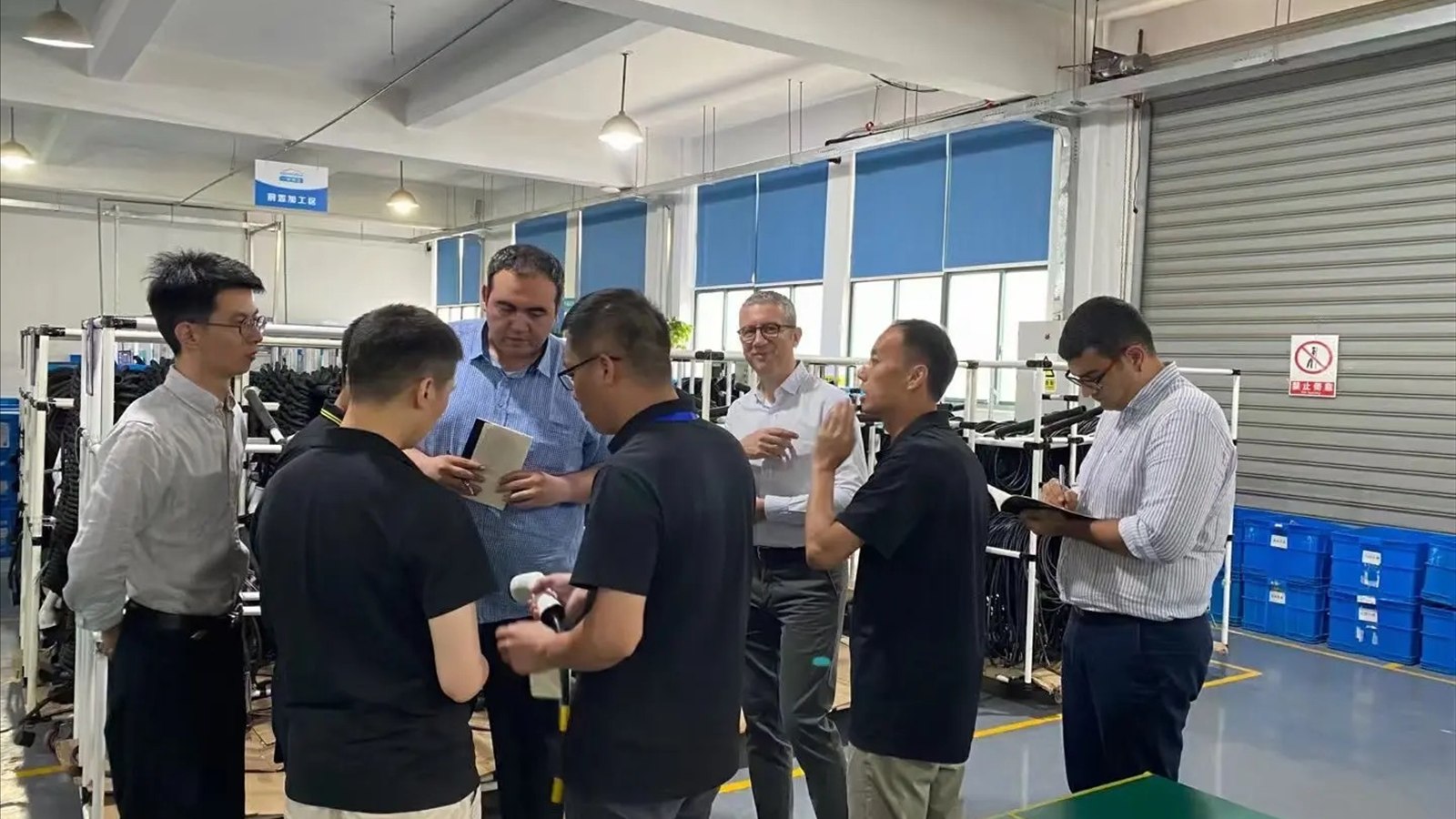 Visitors and supplier staff discussing product details on a factory floor