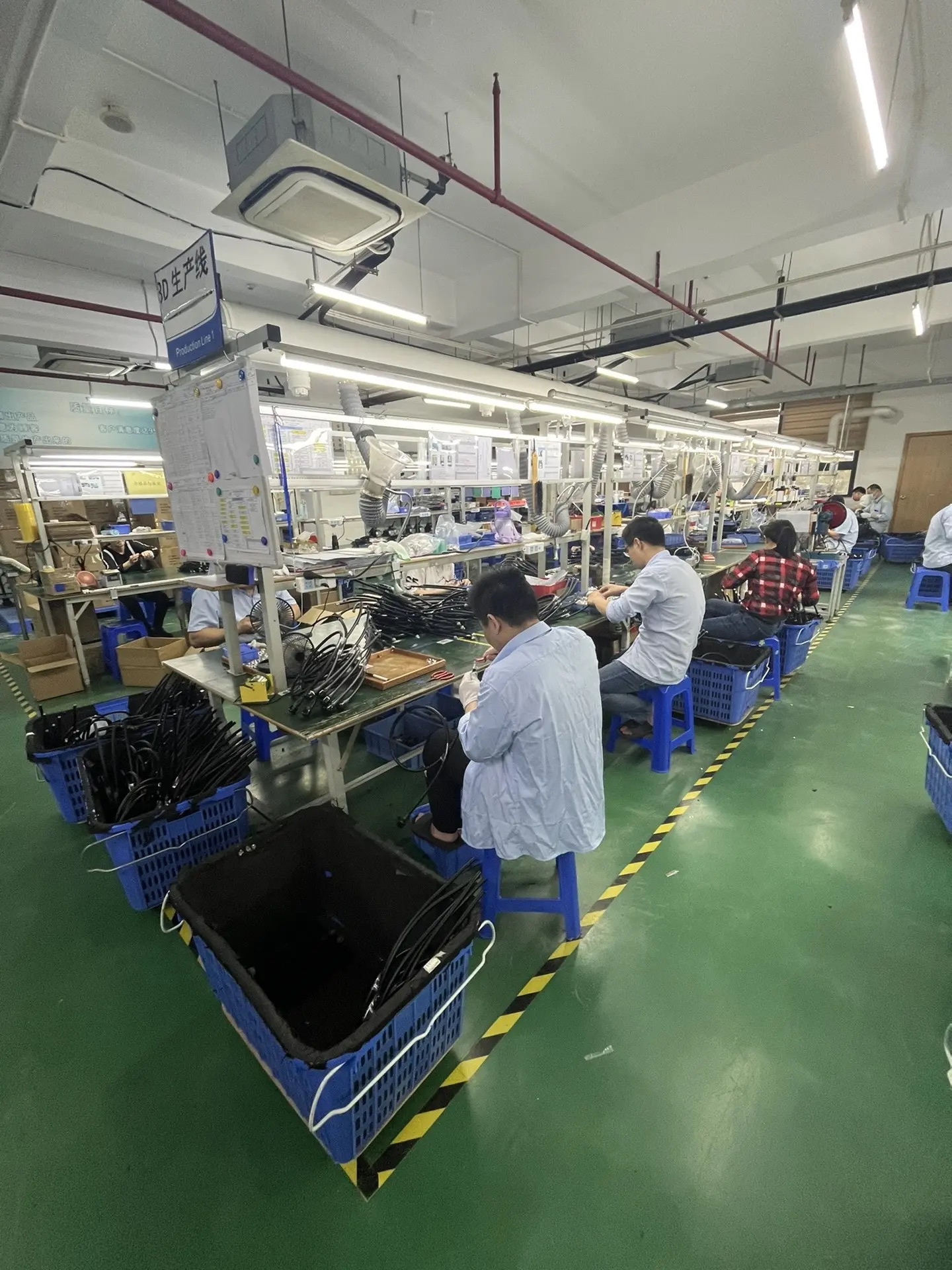 Workers assembling products at workstations along a factory production line